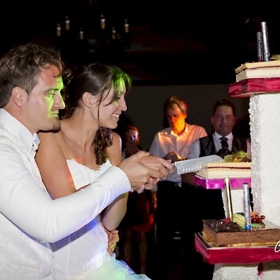 Reportage mariage, photo d'ambiance pendant la soirée le couple coupe le gateau de mariage