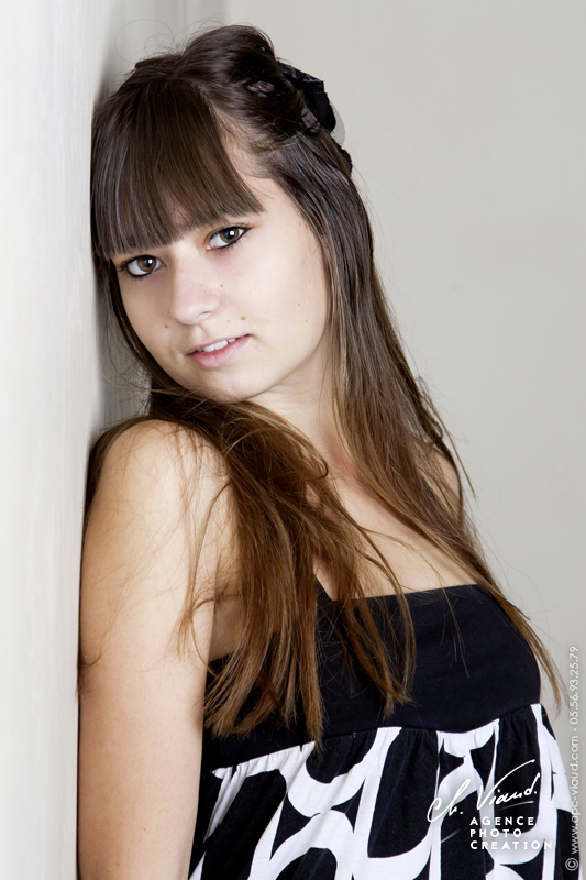 Portrait d'une jeune femme en studio photos appuyée contre un mur