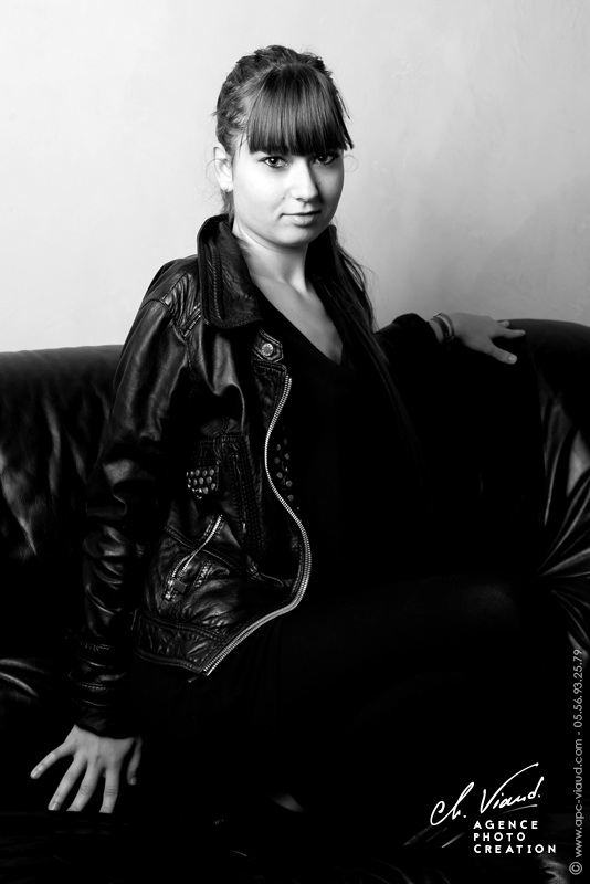 Portrait noir et blanc d'une jeune femme avec une veste en cuir sur un canapé