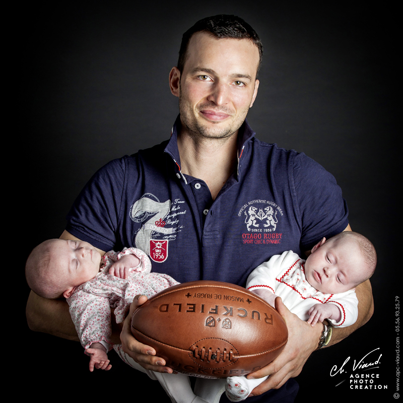 Portrait d'un père avec ses filles dans les bras dans un studio photos