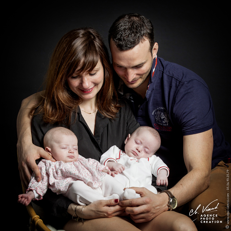 Beau portrait studio d'un couple avec ses deux petites jumelles dans les bras