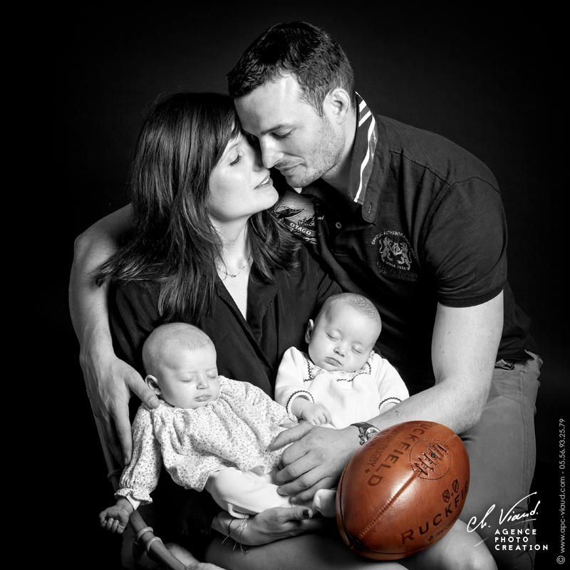 Joli portrait d'un couple en studio photos avec ses deux petites filles dans les bras